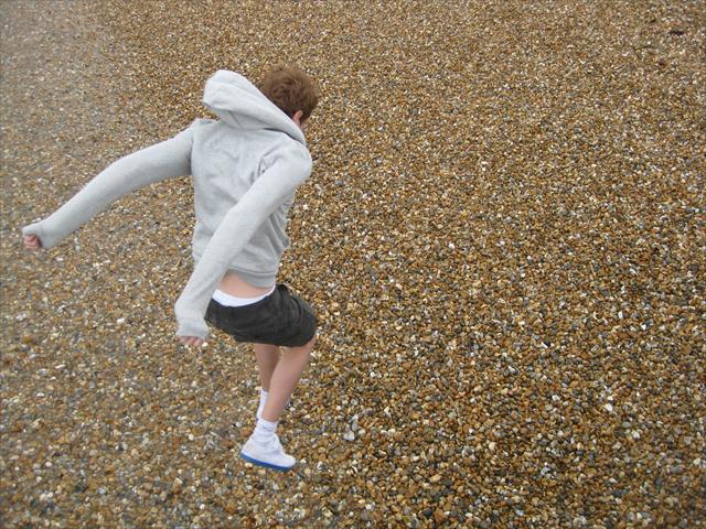 Me jumping onto the pebbles on a beach at Lyme Regis